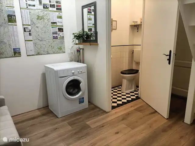 Het halletje met de trap naar boven. Hier is ook de kapstok, een bankje en het toilet. Ook staat hier een wasmachine en een droogrek